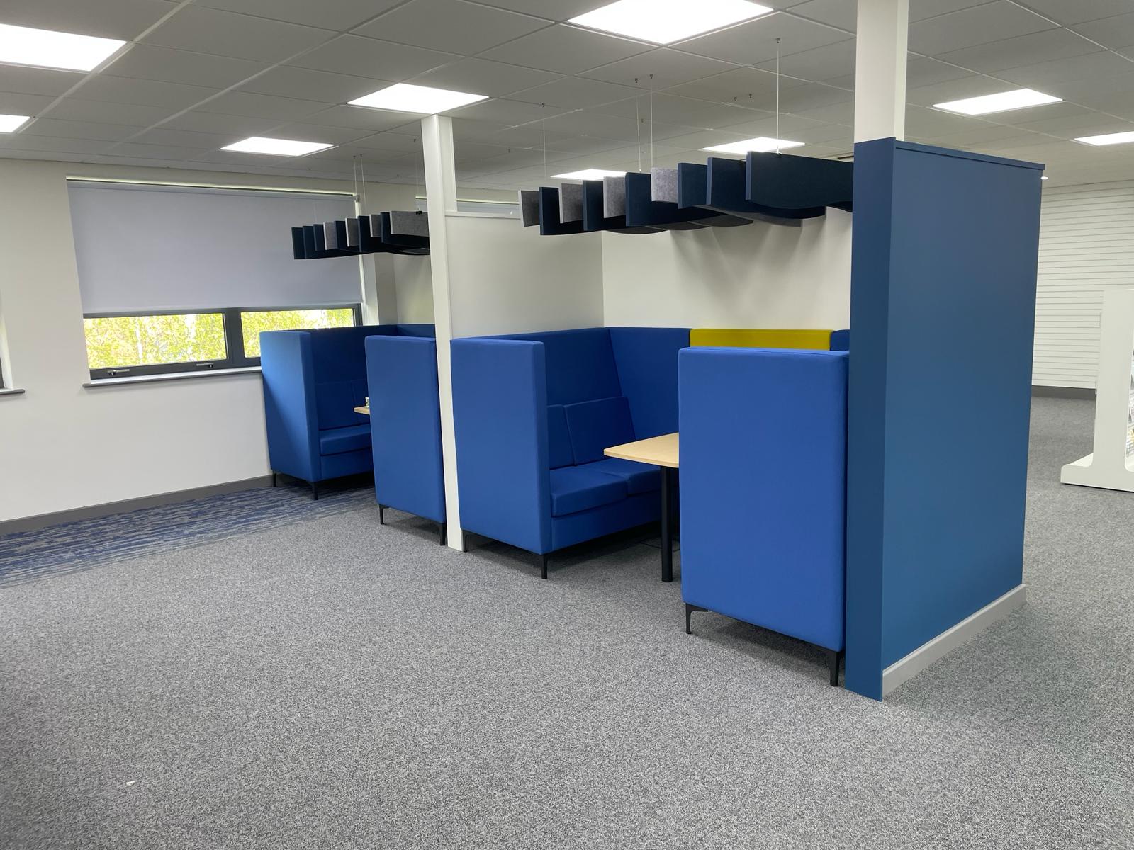 Acoustic meeting booths at Card Factory Wakefield with blue high back seating, small tables and suspended acoustic ceiling baffles