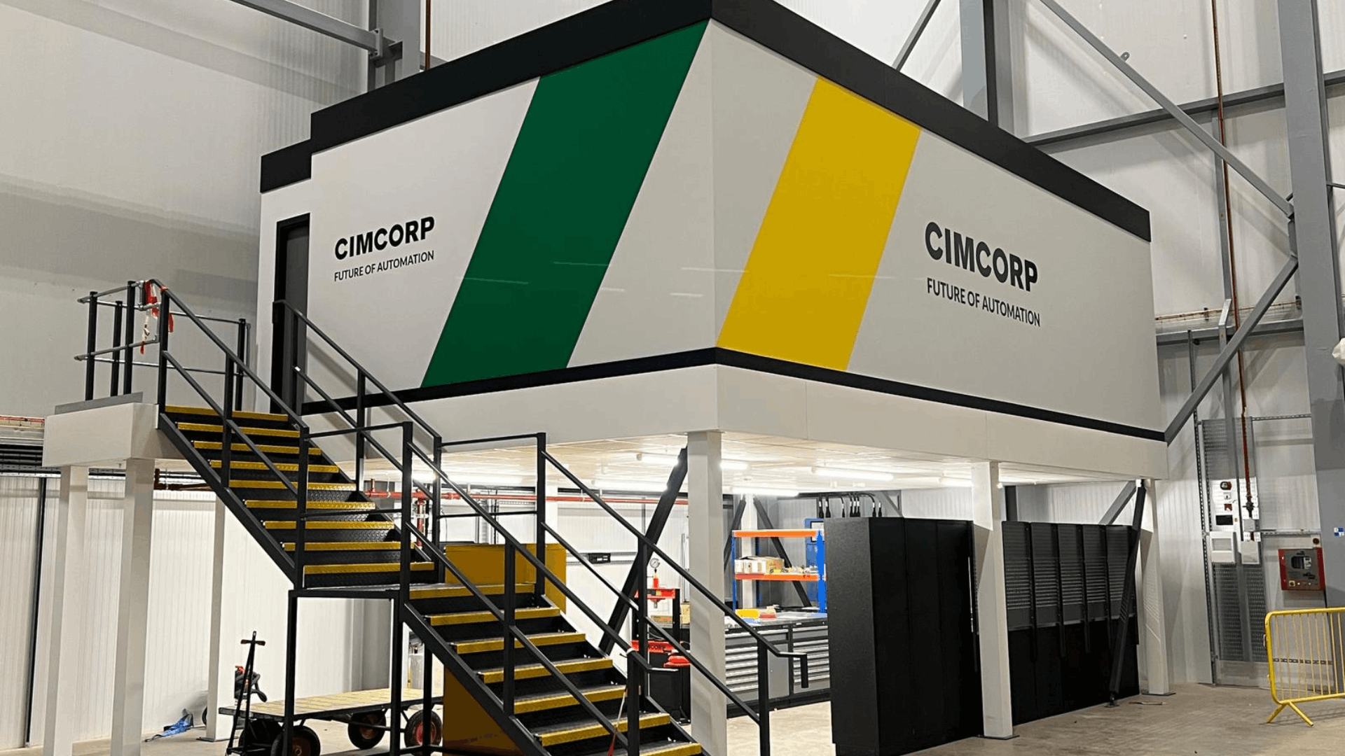 Completed Cimcorp mezzanine office fit out with branded exterior graphics, black staircase, yellow stair nosings and workspace below in a warehouse facility