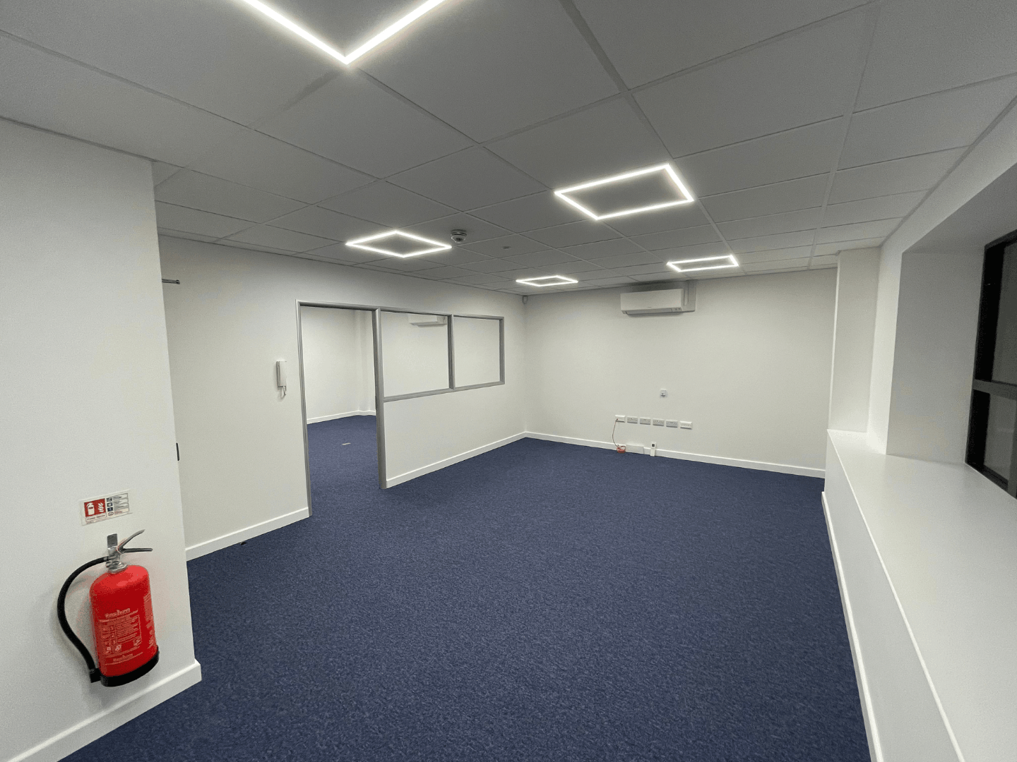 Open plan office space with glazed windows, LED lighting and air conditioning unit