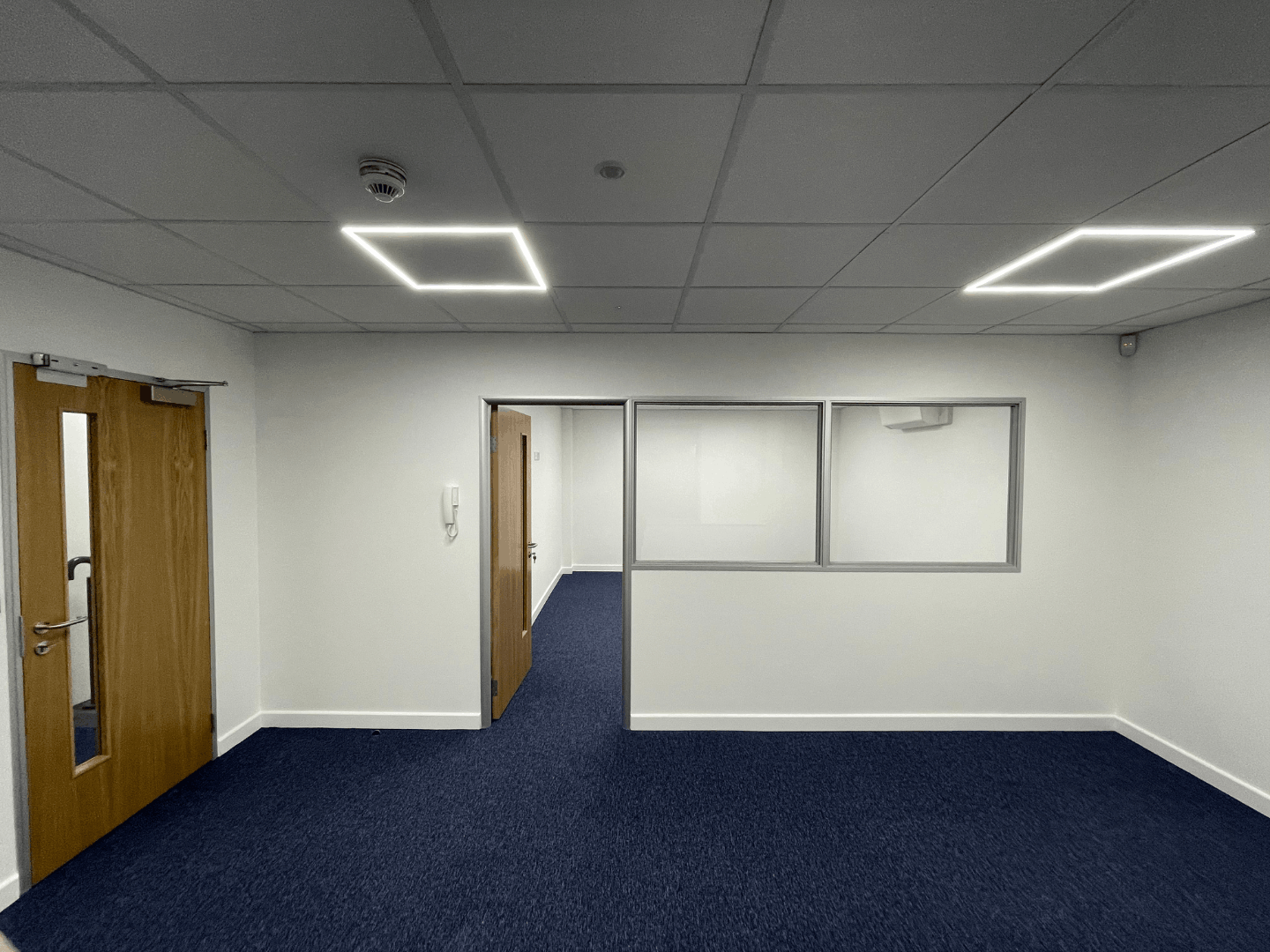 Finished office area with glazed partitioning, blue carpet tiles and LED ceiling lights