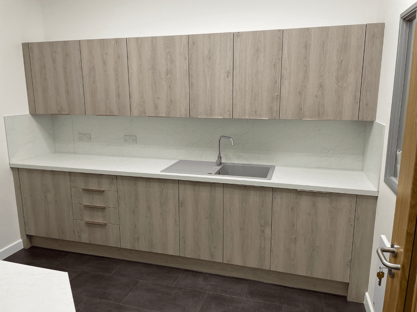 Staff kitchen with grey wood effect units and white worktop at Cromwell Tools Bristol Hub