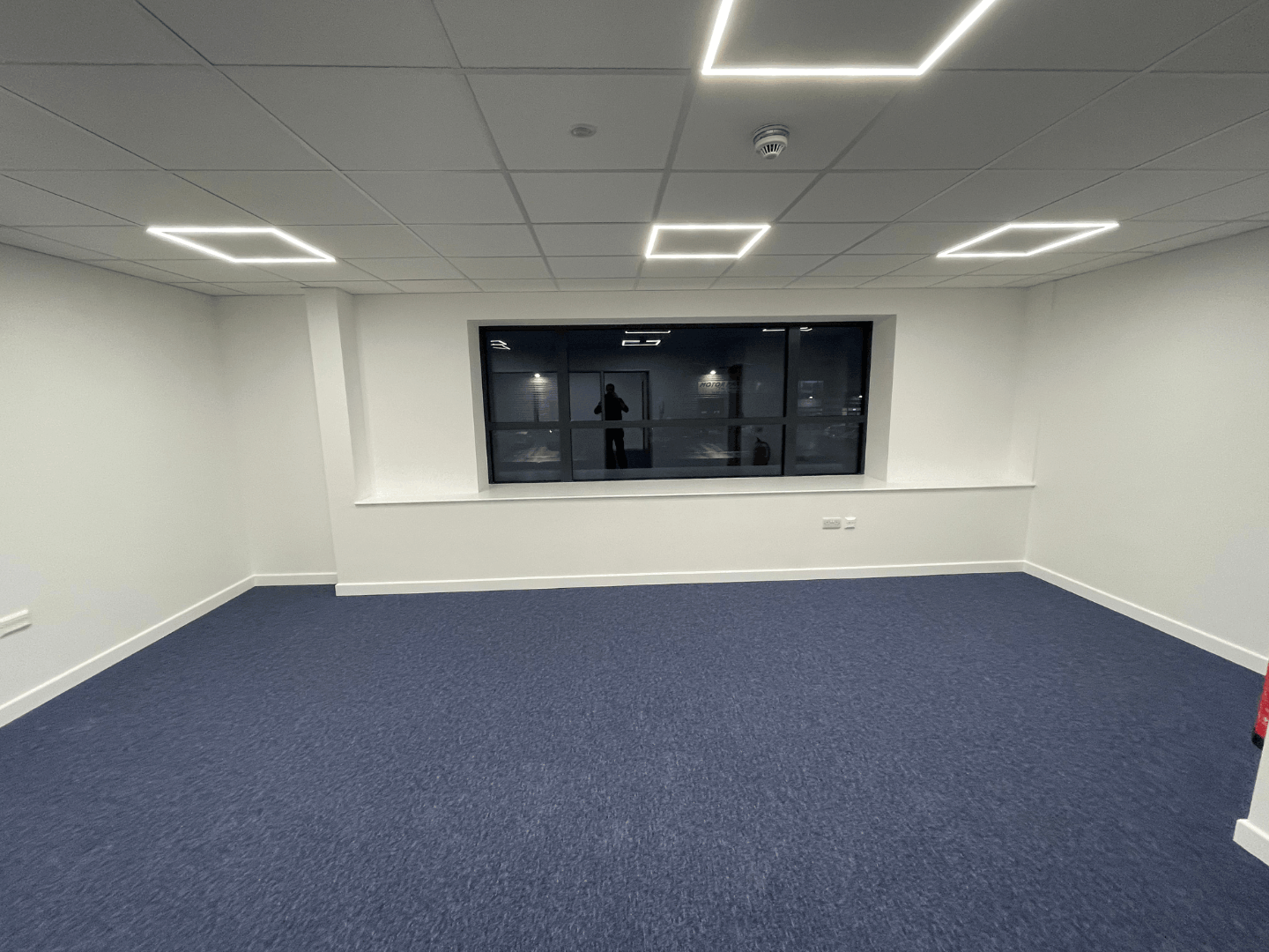 Completed office room with blue carpet tiles, suspended ceiling and LED lighting