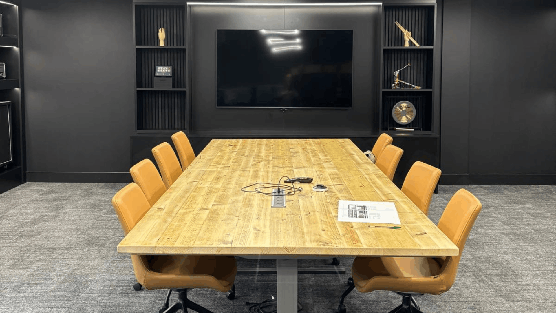 Close-up of the Headstock Group boardroom media wall with black feature joinery, display shelving and wall-mounted screen