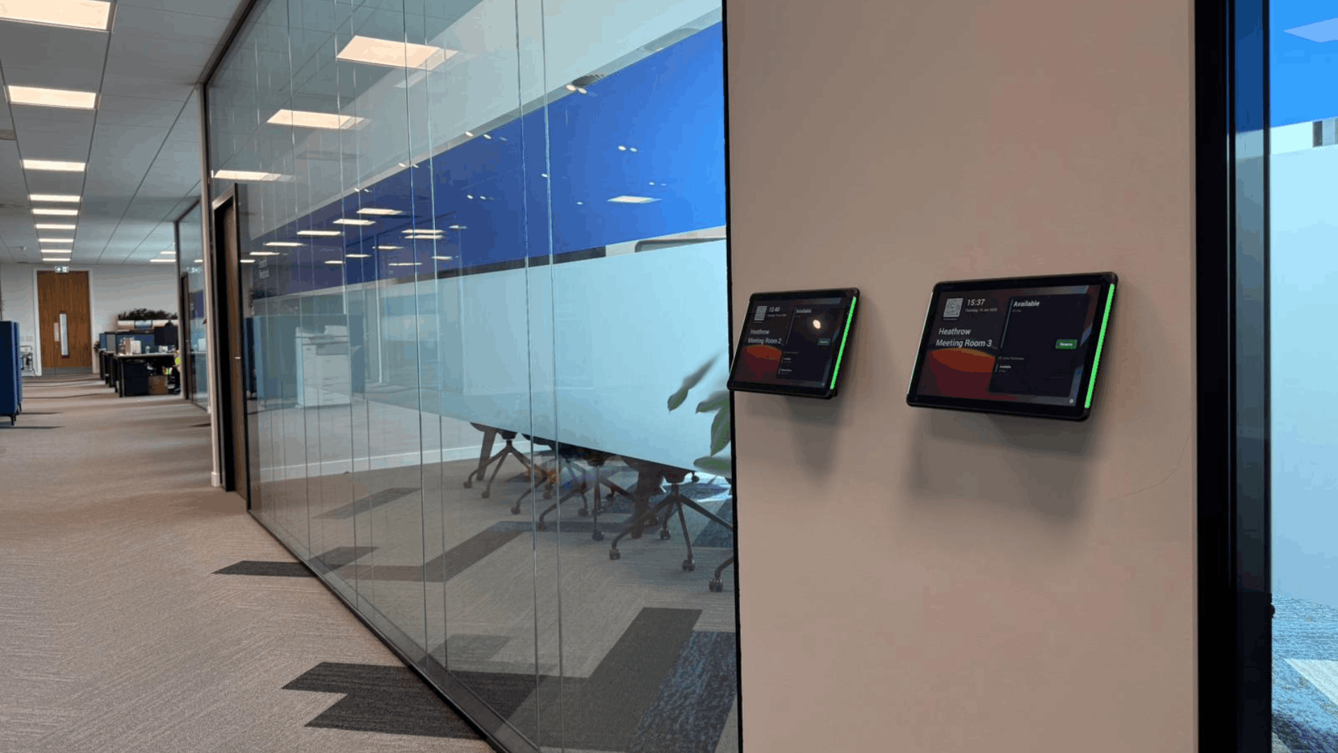 Glass partitioned meeting rooms at Smurfit Westrock with booking screens and blue branded manifestation