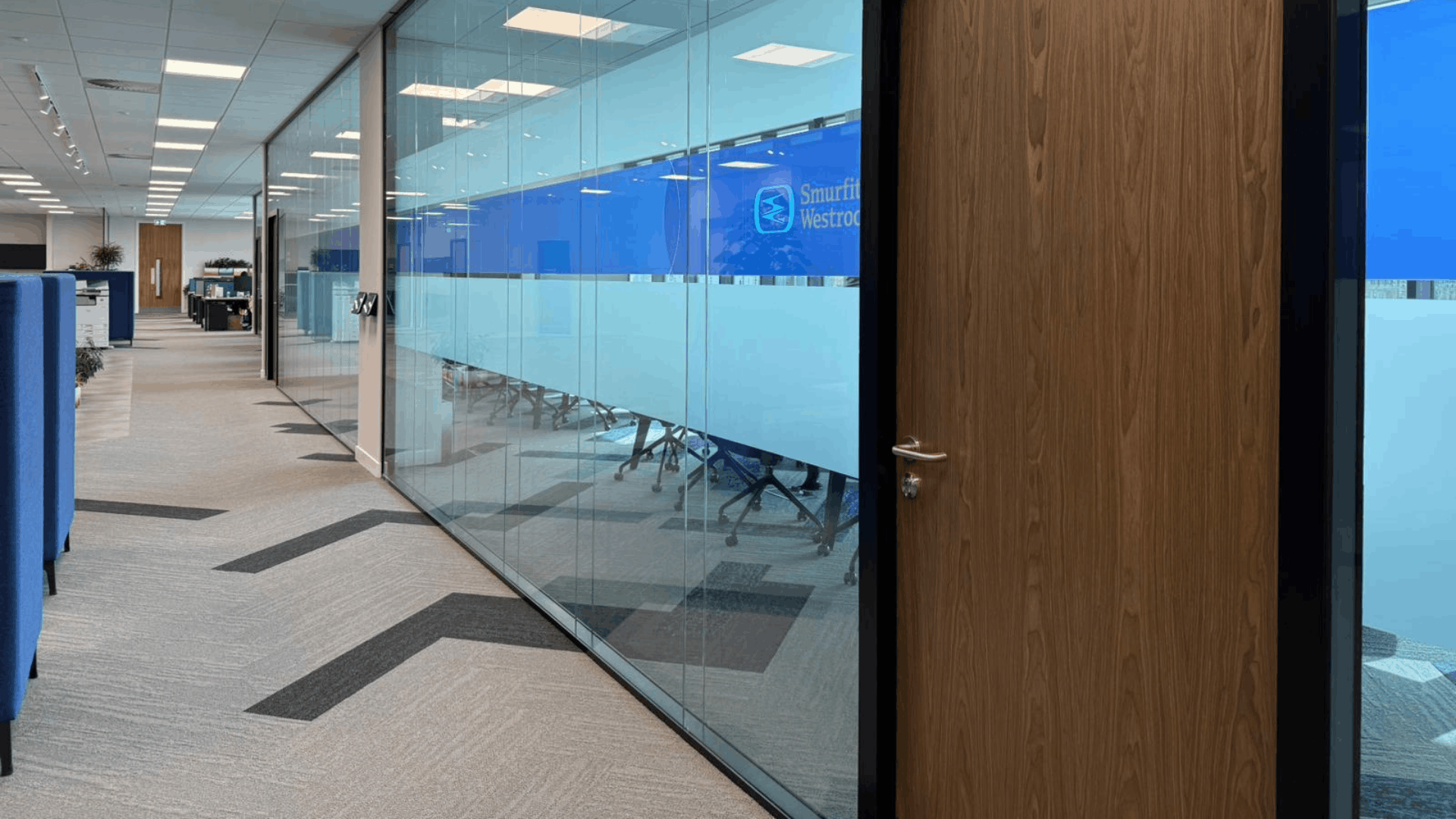 Smurfit Westrock office corridor with glazed partitions, walnut doors and branded blue manifestation